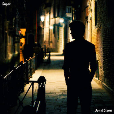 Cover image of the single Super. A silhouetted figure of Jonni Slater standing in a darkened street in Venice, with streetlights creating pools of light along the cobbled walkway that recedes into the distance.