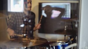 Doug playing drums in Chris's studio, taken through the glass of the drum booth.
Photo by Jonni Slater